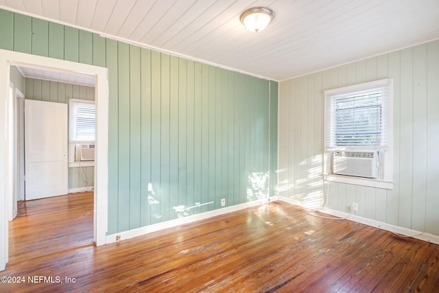 spare room with wood walls, hardwood / wood-style floors, wooden ceiling, and cooling unit