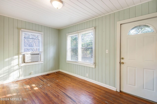 foyer with a wealth of natural light, wooden walls, and wood-type flooring