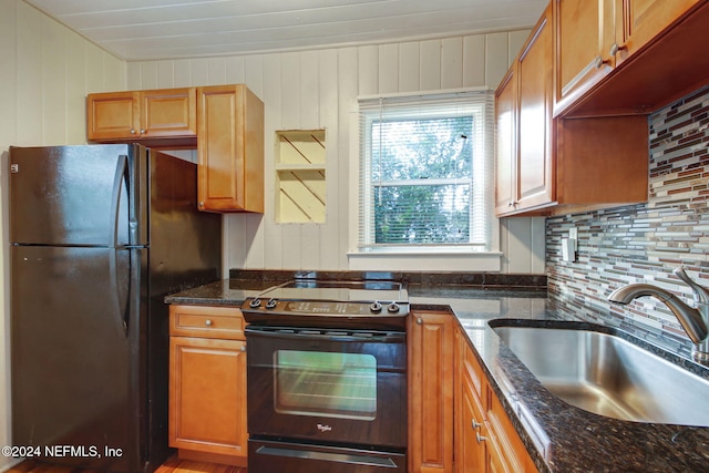 kitchen with electric stove, wood walls, backsplash, and black fridge