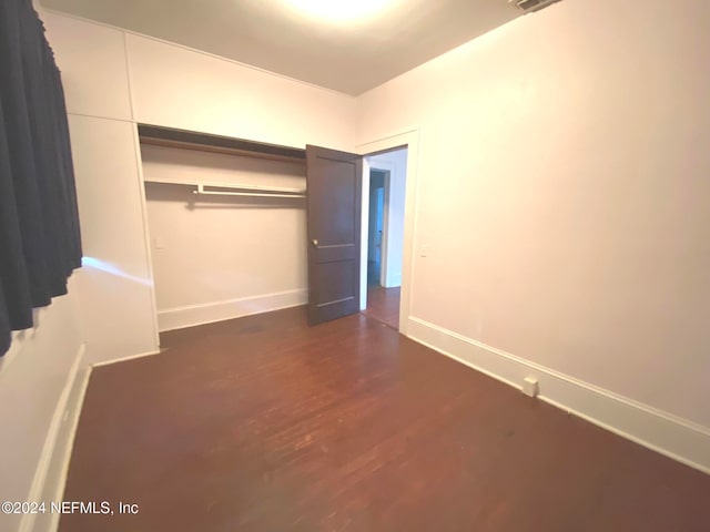 unfurnished bedroom with dark hardwood / wood-style flooring and a closet