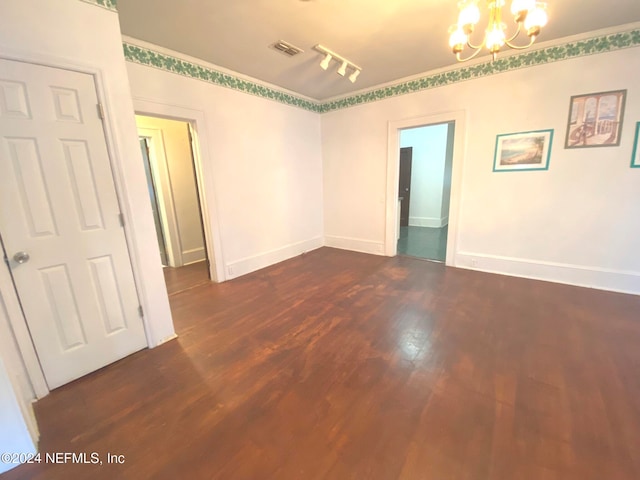 spare room with a notable chandelier, dark hardwood / wood-style flooring, and track lighting