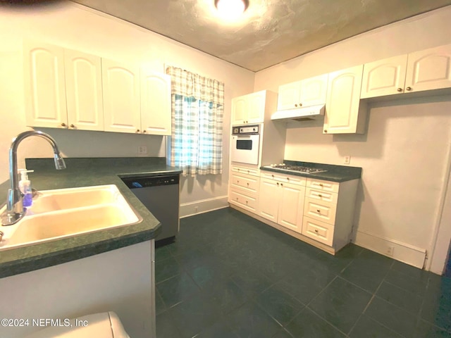 kitchen featuring stainless steel appliances, white cabinetry, dark tile patterned floors, and sink