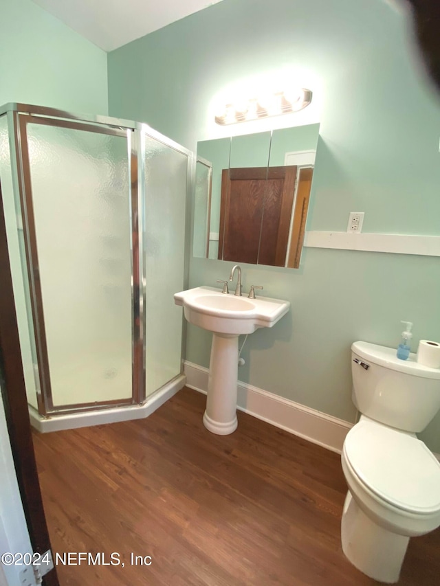 bathroom with hardwood / wood-style floors, a shower with door, and toilet