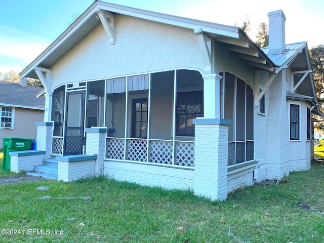 view of home's exterior featuring a lawn and a sunroom