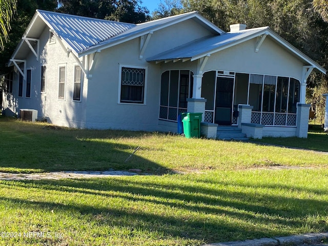 view of front of property featuring central AC, a sunroom, and a front yard