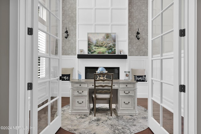 home office with hardwood / wood-style flooring, built in desk, and french doors