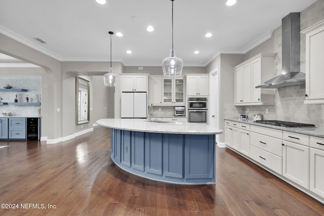 kitchen with stainless steel appliances, wall chimney exhaust hood, an island with sink, dark hardwood / wood-style floors, and white cabinetry