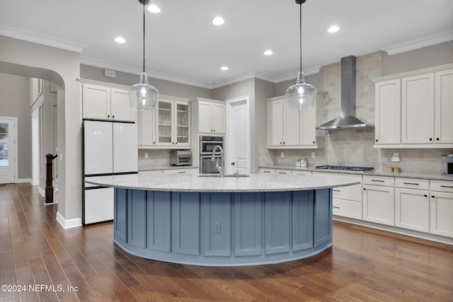 kitchen with appliances with stainless steel finishes, wall chimney exhaust hood, white cabinetry, and dark hardwood / wood-style floors