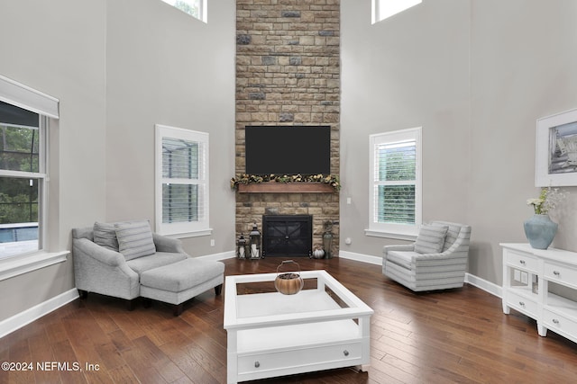 living room with a fireplace, a towering ceiling, and dark hardwood / wood-style floors