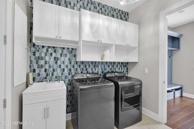 laundry room featuring washer and clothes dryer, cabinets, sink, and light hardwood / wood-style floors