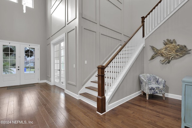 foyer with dark hardwood / wood-style flooring, a wealth of natural light, french doors, and a towering ceiling