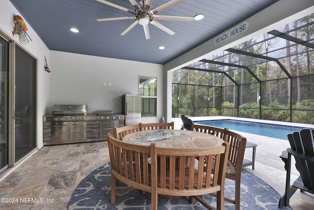 view of patio featuring ceiling fan, a grill, glass enclosure, and exterior kitchen