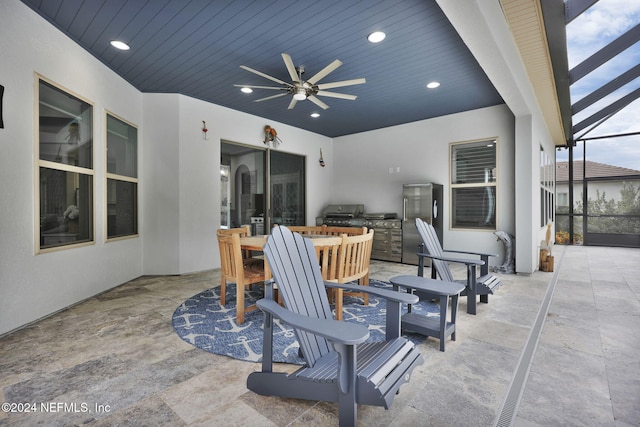 view of patio with glass enclosure, exterior kitchen, and ceiling fan