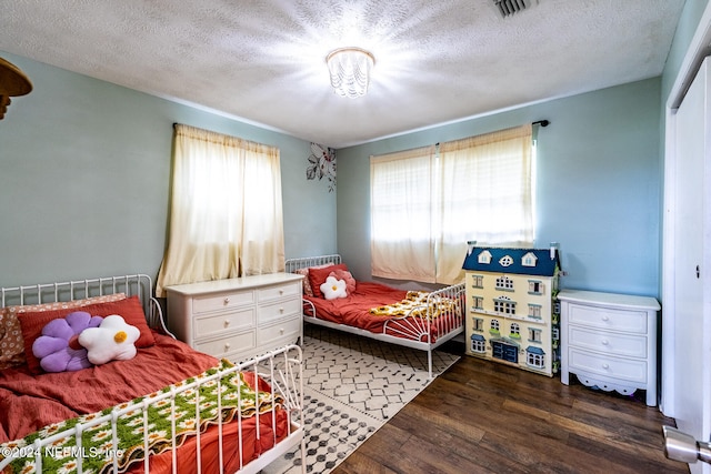 bedroom featuring dark hardwood / wood-style flooring and a textured ceiling