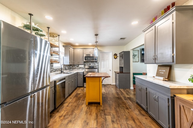 kitchen featuring pendant lighting, sink, dark hardwood / wood-style floors, gray cabinets, and appliances with stainless steel finishes