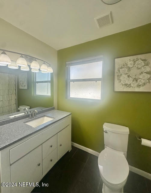 bathroom with toilet, vanity, and tile patterned floors