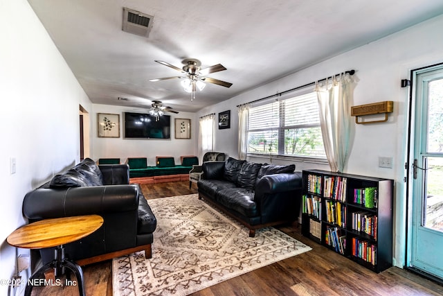 living room with ceiling fan and dark wood-type flooring