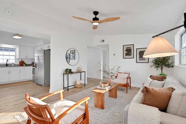 living room with sink, light hardwood / wood-style floors, vaulted ceiling, and ceiling fan