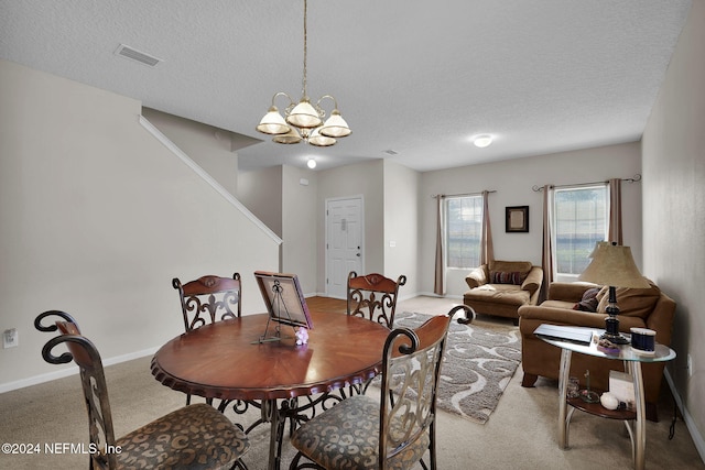 carpeted dining room featuring a chandelier and a textured ceiling