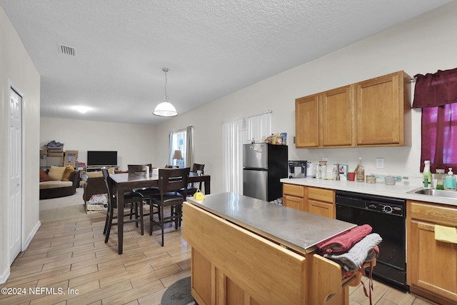 kitchen featuring black dishwasher, hanging light fixtures, a textured ceiling, sink, and stainless steel refrigerator