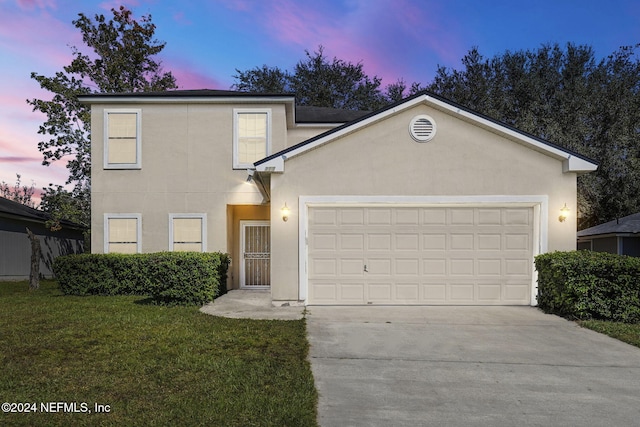 front facade featuring a garage and a yard