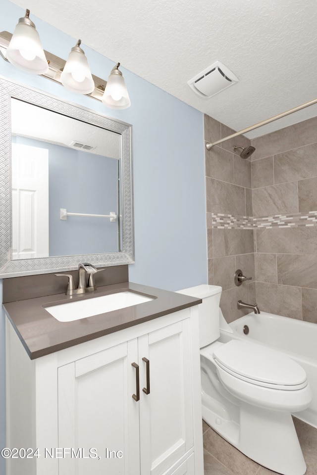 full bathroom featuring toilet, tile patterned floors, tiled shower / bath, a textured ceiling, and vanity