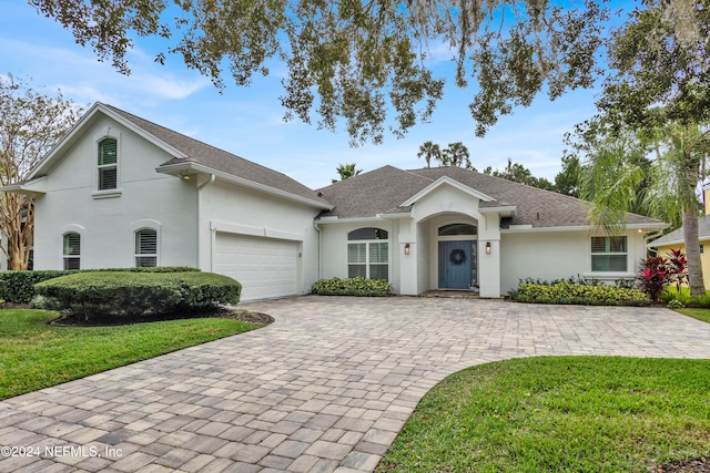 ranch-style home with a garage and a front lawn