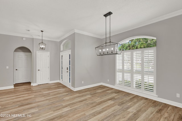 spare room with ornamental molding, light hardwood / wood-style floors, and an inviting chandelier