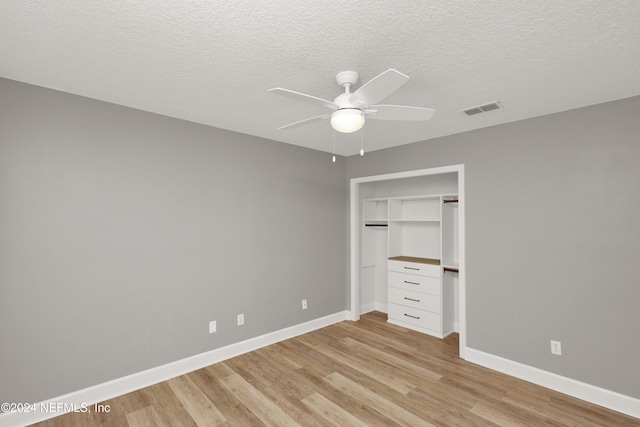 unfurnished bedroom with a closet, light wood-type flooring, a textured ceiling, and ceiling fan