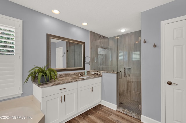 bathroom with vanity, hardwood / wood-style flooring, a textured ceiling, and shower with separate bathtub