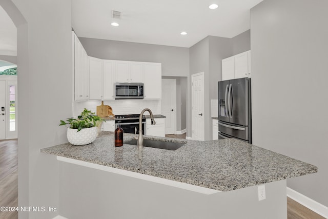 kitchen featuring stainless steel appliances, white cabinets, sink, and kitchen peninsula