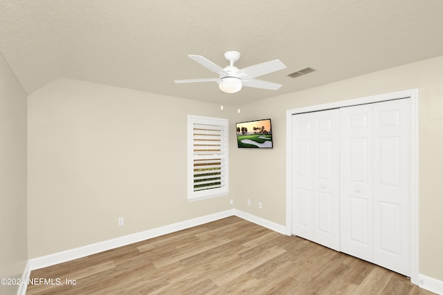 unfurnished bedroom with a textured ceiling, light hardwood / wood-style flooring, ceiling fan, and a closet