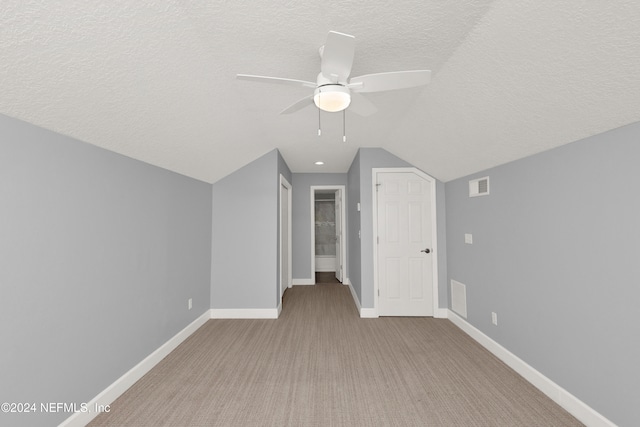 bonus room featuring lofted ceiling, a textured ceiling, light carpet, and ceiling fan