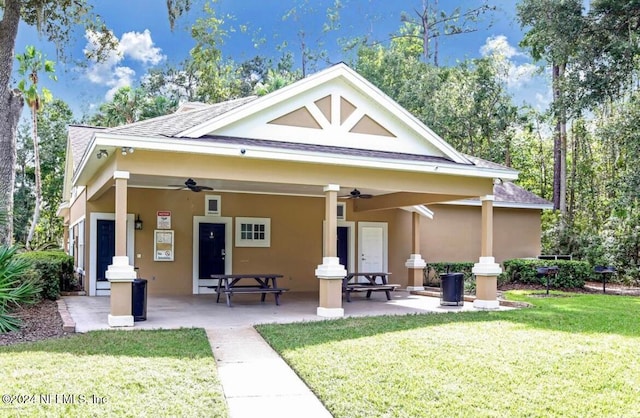 back of house with ceiling fan and a yard