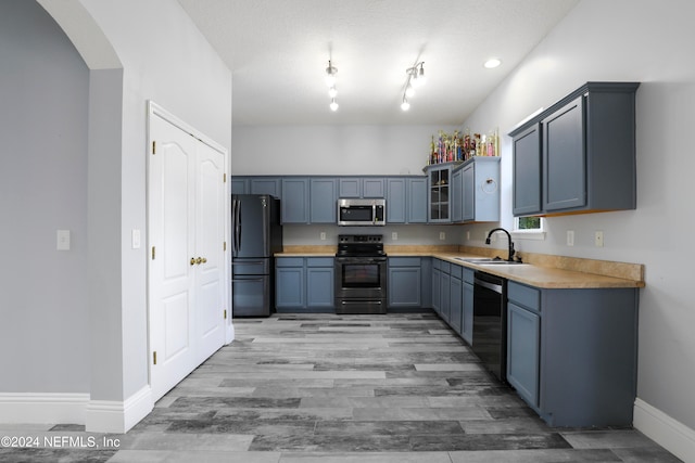 kitchen with light hardwood / wood-style floors, blue cabinets, black appliances, a textured ceiling, and sink