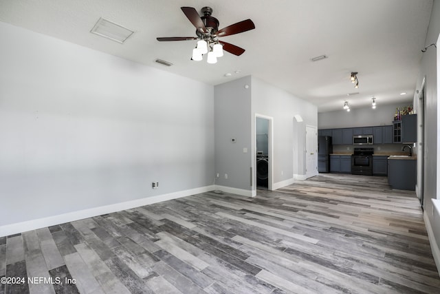 unfurnished living room with ceiling fan, sink, and light hardwood / wood-style flooring