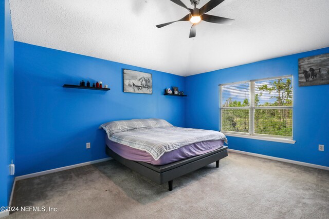 carpeted bedroom with ceiling fan and a textured ceiling