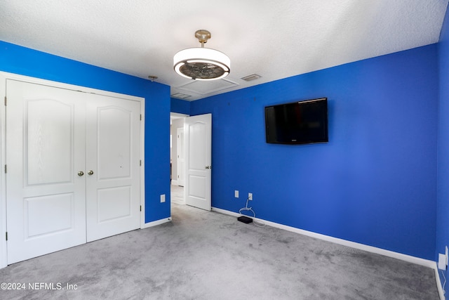 unfurnished bedroom with a closet, a textured ceiling, and light colored carpet