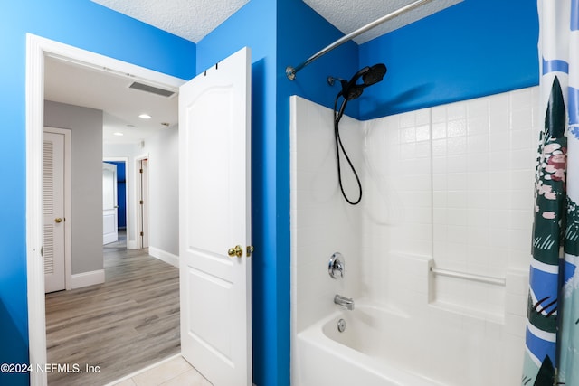 bathroom featuring shower / tub combo, hardwood / wood-style floors, and a textured ceiling