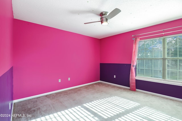 spare room featuring a textured ceiling, carpet floors, and ceiling fan