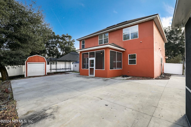 view of front facade featuring an outbuilding, a garage, a sunroom, and a patio