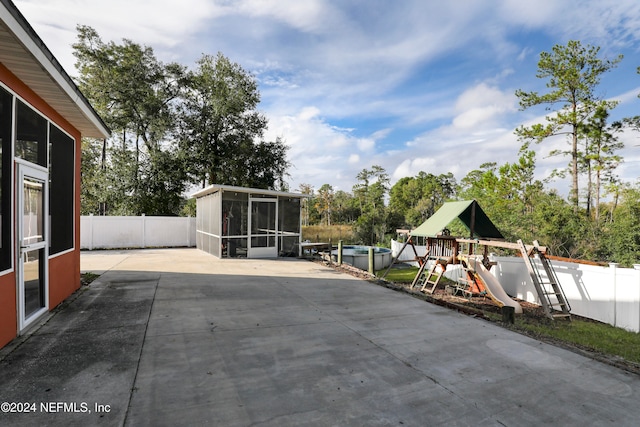 view of patio / terrace with a playground, a sunroom, and a fenced in pool