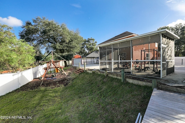 view of yard featuring a patio, a sunroom, a storage shed, and a playground