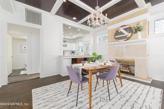 dining space with coffered ceiling, dark hardwood / wood-style floors, a fireplace, and a chandelier