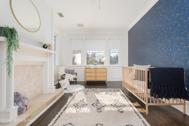 bedroom with crown molding, dark wood-type flooring, and a crib