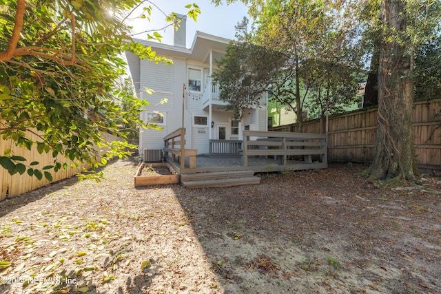 rear view of property featuring cooling unit and a wooden deck