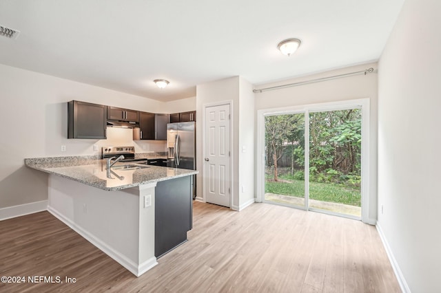 kitchen featuring light stone countertops, dark brown cabinetry, light wood-type flooring, and kitchen peninsula