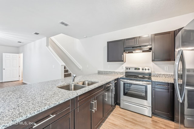 kitchen featuring kitchen peninsula, sink, light stone countertops, appliances with stainless steel finishes, and light hardwood / wood-style floors