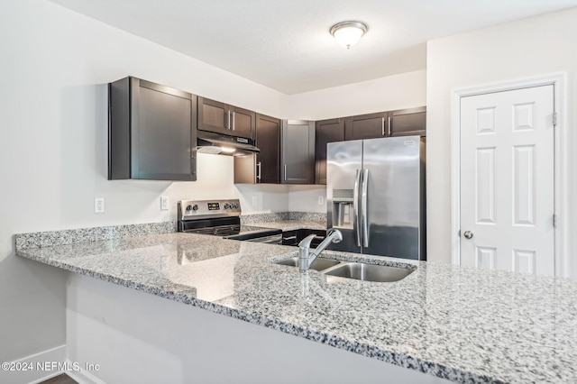 kitchen featuring kitchen peninsula, light stone counters, sink, dark brown cabinetry, and stainless steel appliances