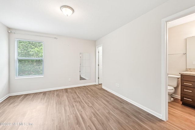 unfurnished bedroom with connected bathroom and light hardwood / wood-style floors